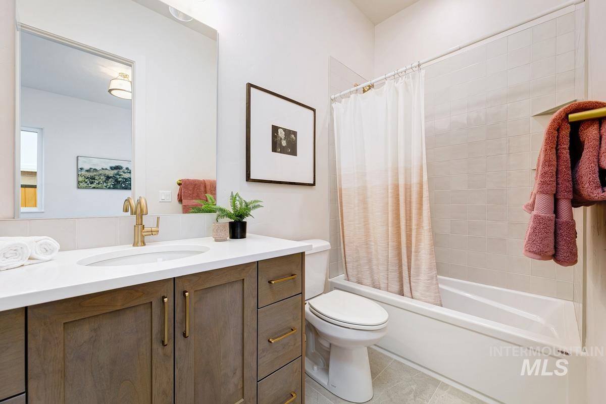 Bathroom featuring vanity, shower / tub combo with curtain, and light tile patterned floors