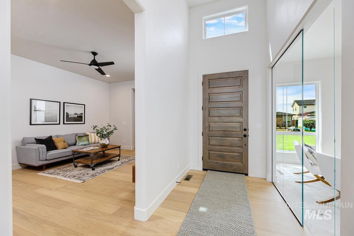 Entrance foyer featuring ceiling fan, light wood-style flooring, and a high ceiling