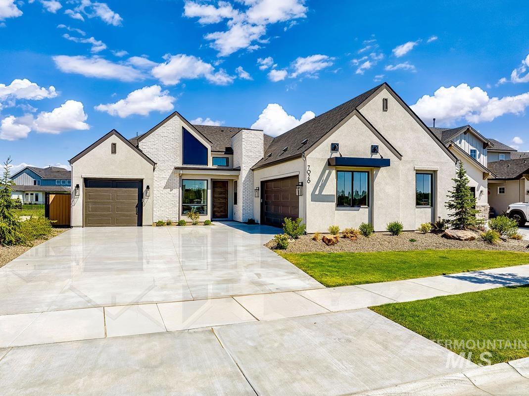 Modern farmhouse style home featuring a garage, concrete driveway, stucco siding, and a front lawn