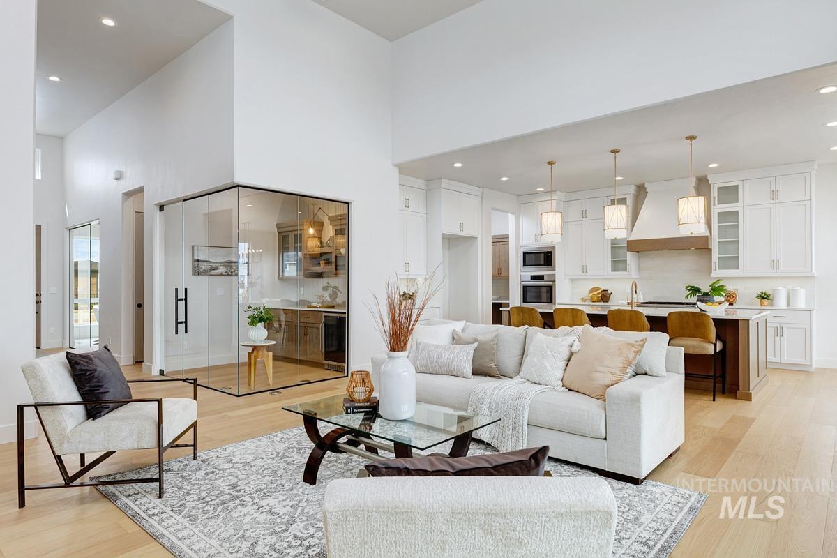 Living area featuring light wood-type flooring, recessed lighting, a towering ceiling, and wine cooler