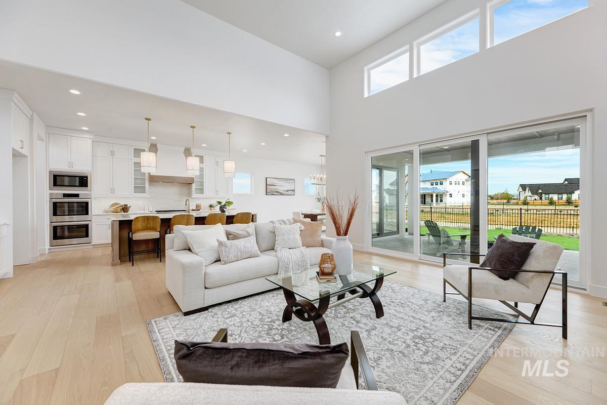 Living room with light wood-style flooring, a towering ceiling, and recessed lighting