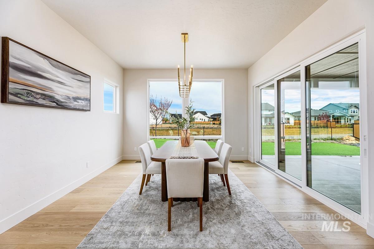 Dining area with a residential view, light wood finished floors, and a chandelier