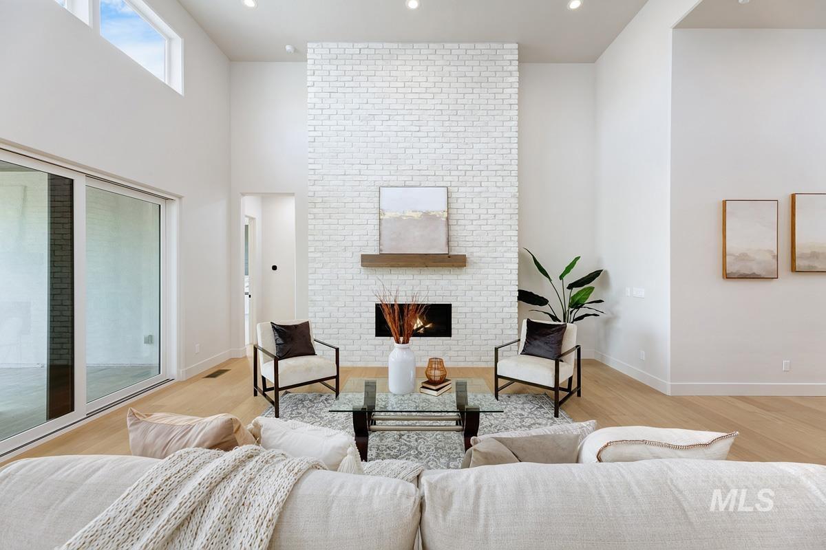 Living area with a brick fireplace, recessed lighting, a towering ceiling, and light wood-style flooring
