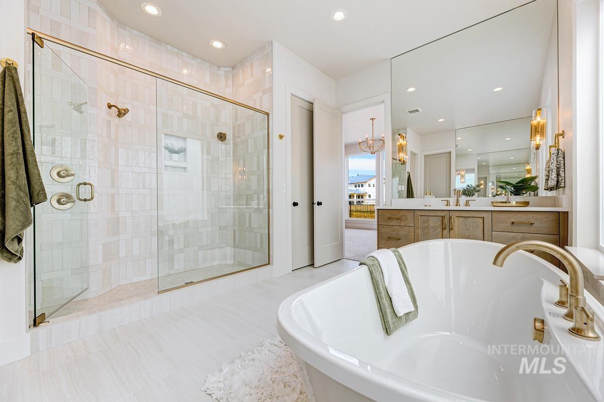 Bathroom with a freestanding bath, vanity, a chandelier, a shower stall, and recessed lighting