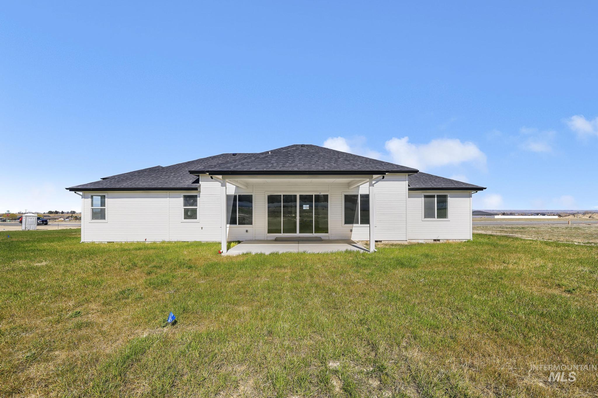 Rear view of property featuring a patio area, a yard, and roof with shingles