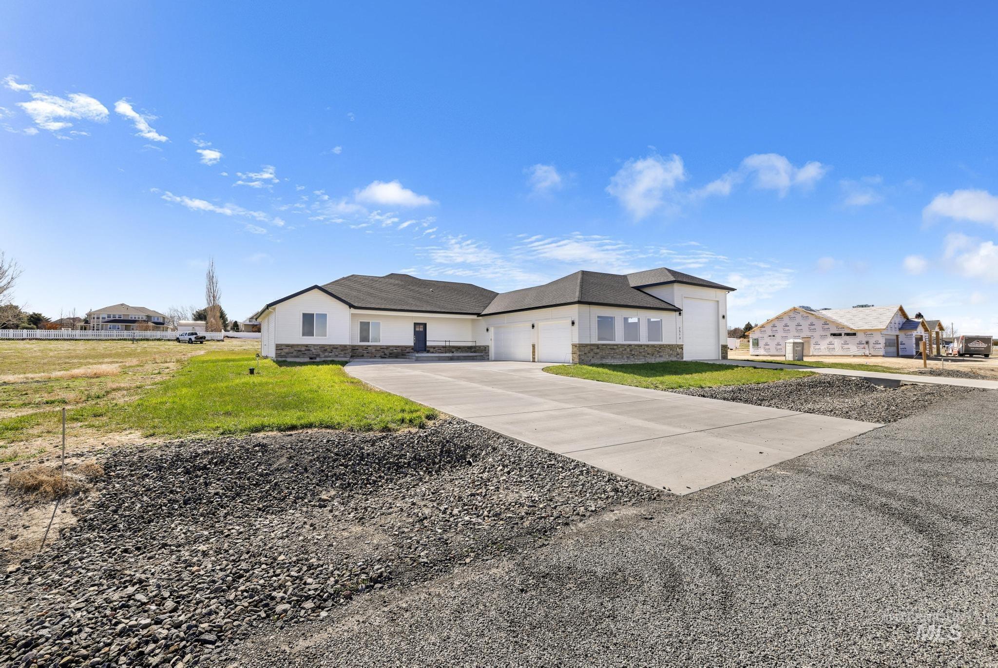 View of front facade featuring stone siding, a front yard, an attached garage, and concrete driveway