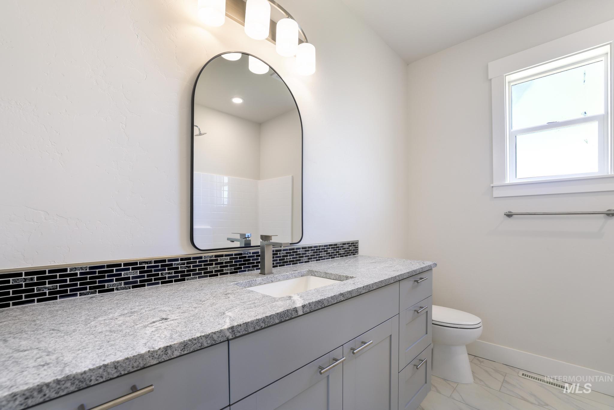 Full bath with vanity, light marble finish flooring, a shower, and tasteful backsplash