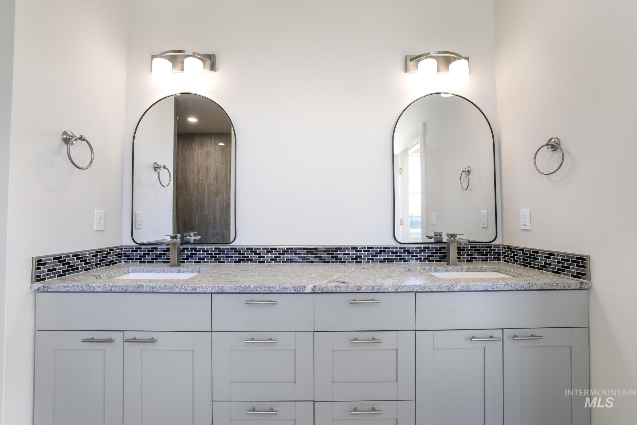 Full bath featuring double vanity and decorative backsplash