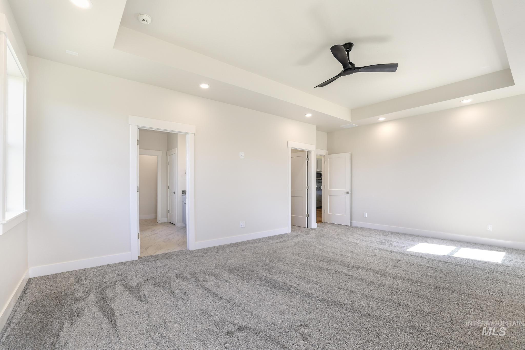 Unfurnished bedroom with a tray ceiling, light colored carpet, ceiling fan, and recessed lighting