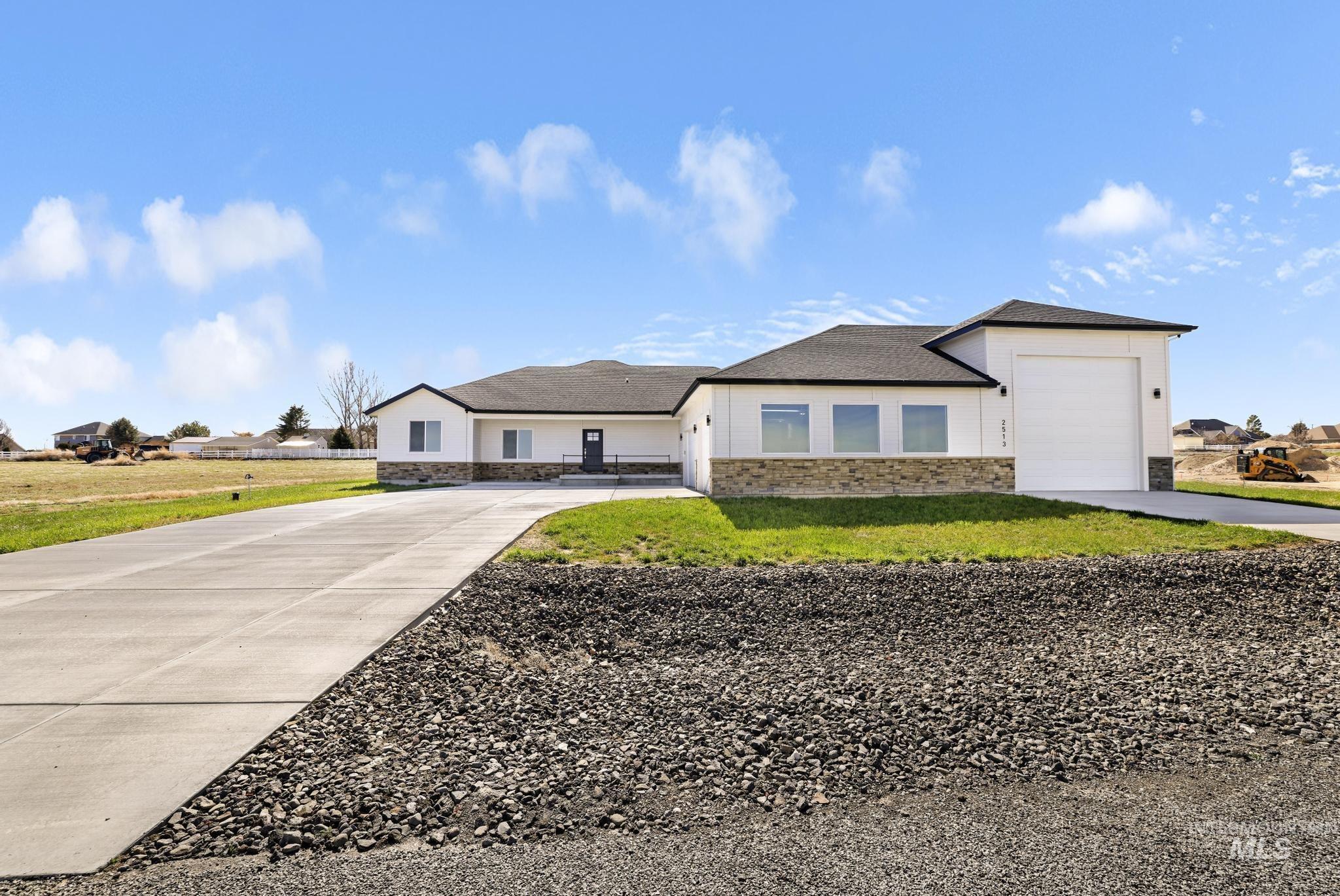 View of front of property featuring stone siding, driveway, an attached garage, and a front lawn
