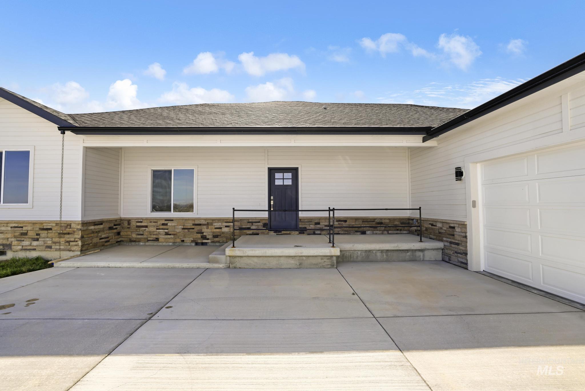 Doorway to property featuring stone siding, a patio, and a garage