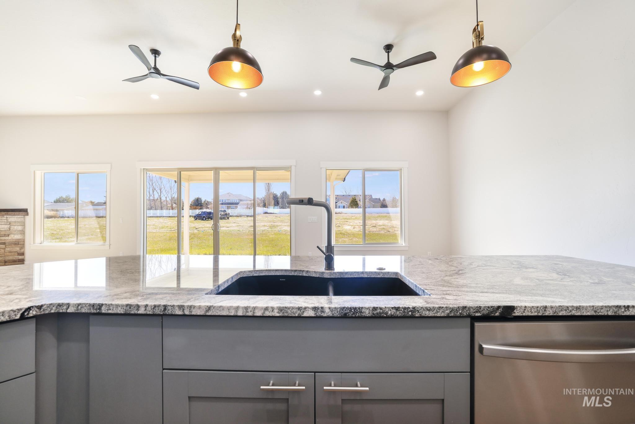 Kitchen with a ceiling fan, dishwasher, light stone countertops, gray cabinetry, and pendant lighting