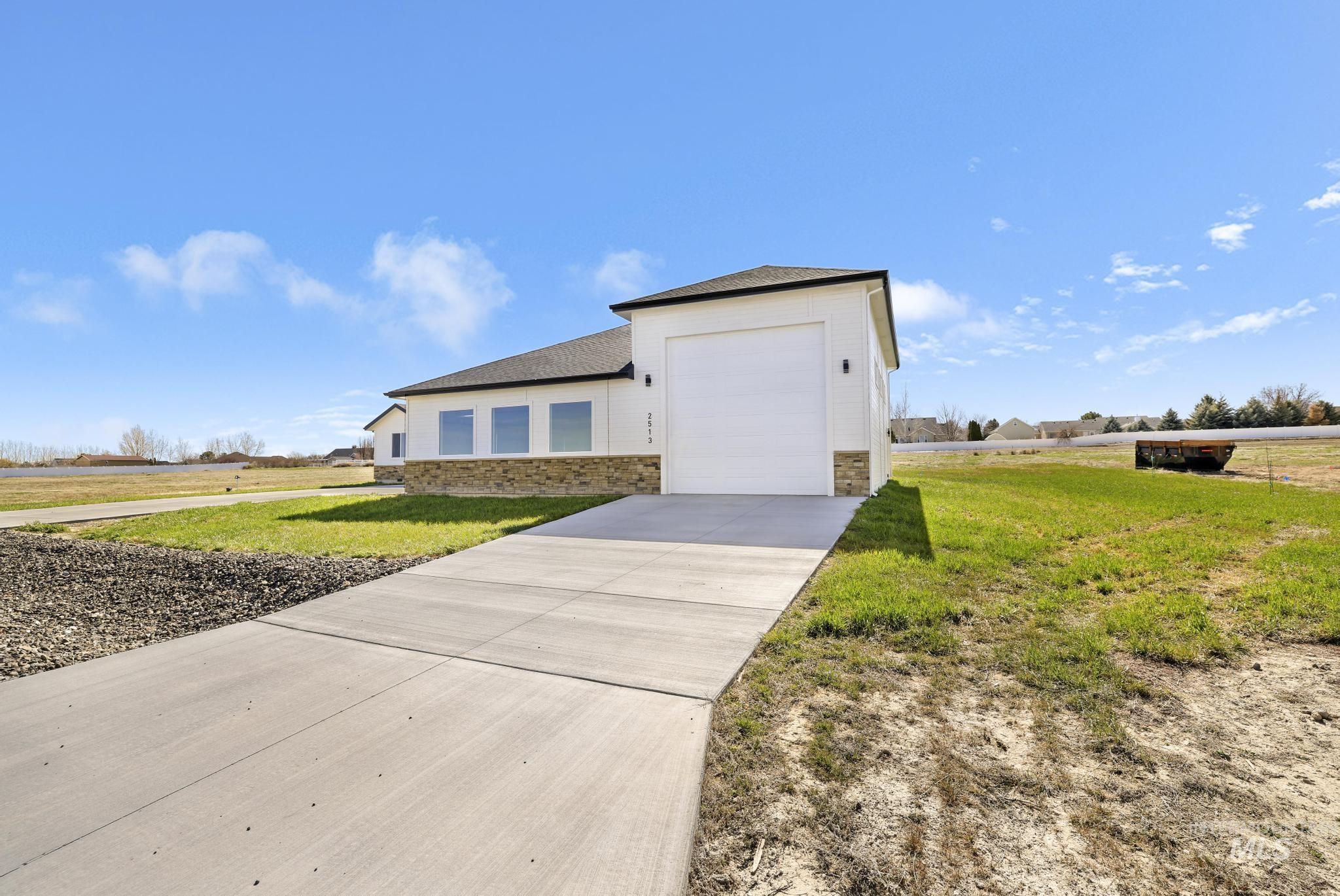 View of front of house with stone siding, concrete driveway, a shingled roof, and a front lawn