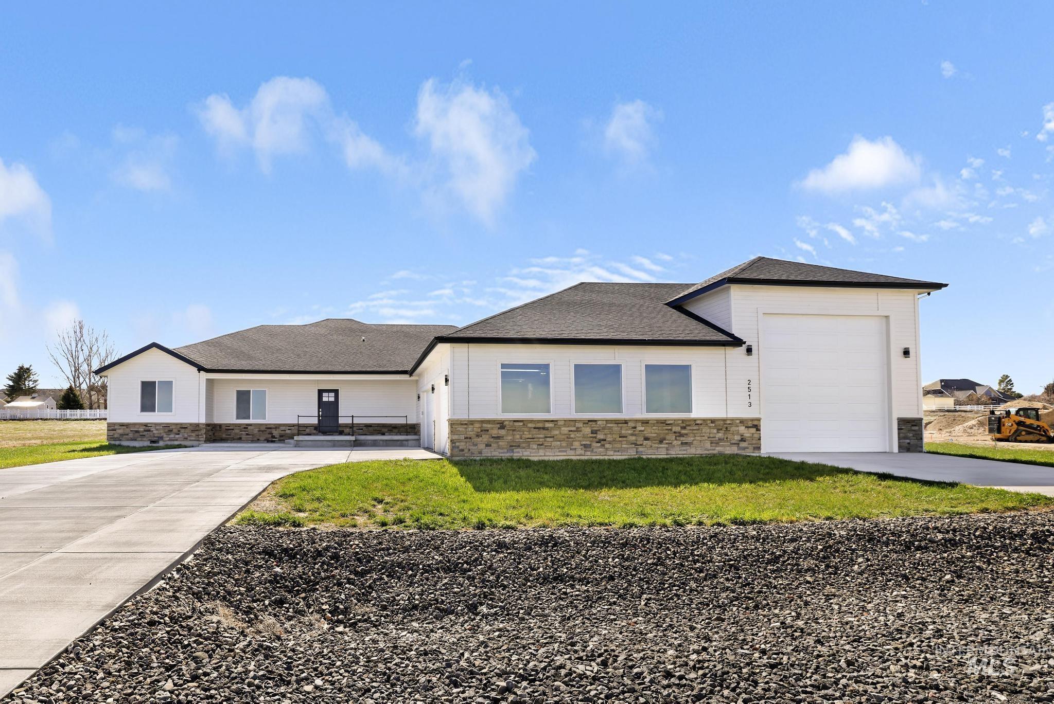 View of front of property featuring stone siding, a garage, driveway, and a front lawn