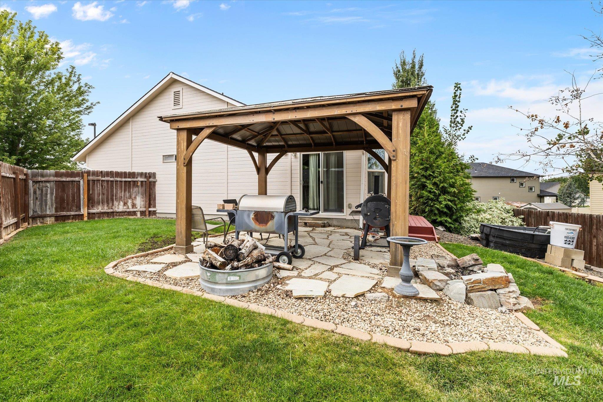 Fenced backyard with a gazebo, a fire pit, and a patio area