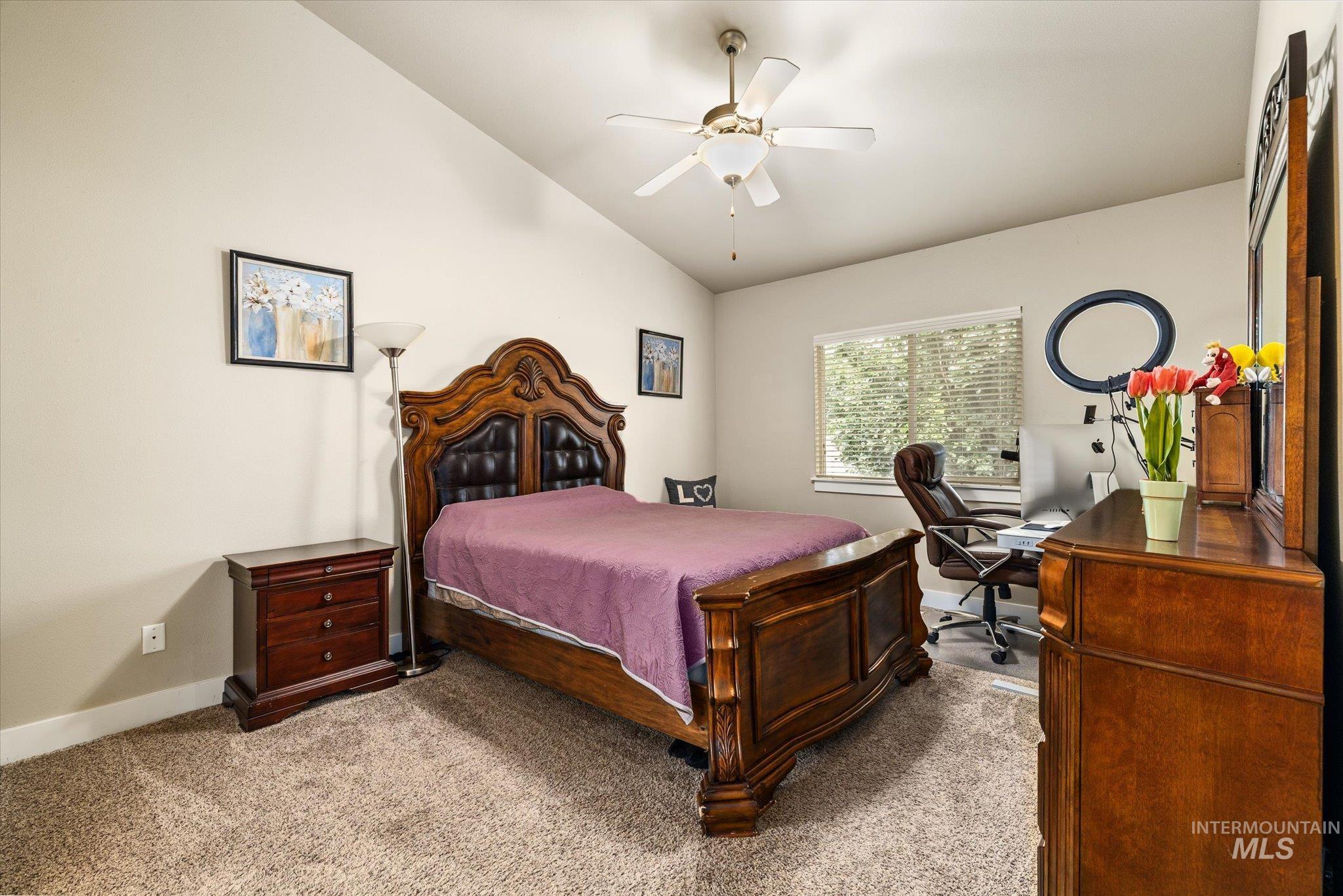 Carpeted bedroom with vaulted ceiling, a desk, and ceiling fan