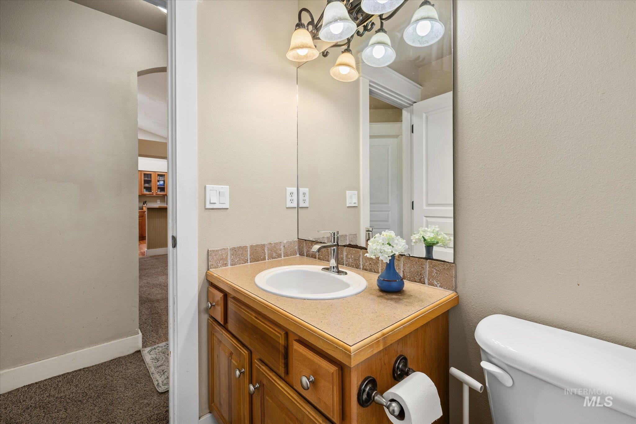 Bathroom featuring vanity, a textured wall, and a chandelier