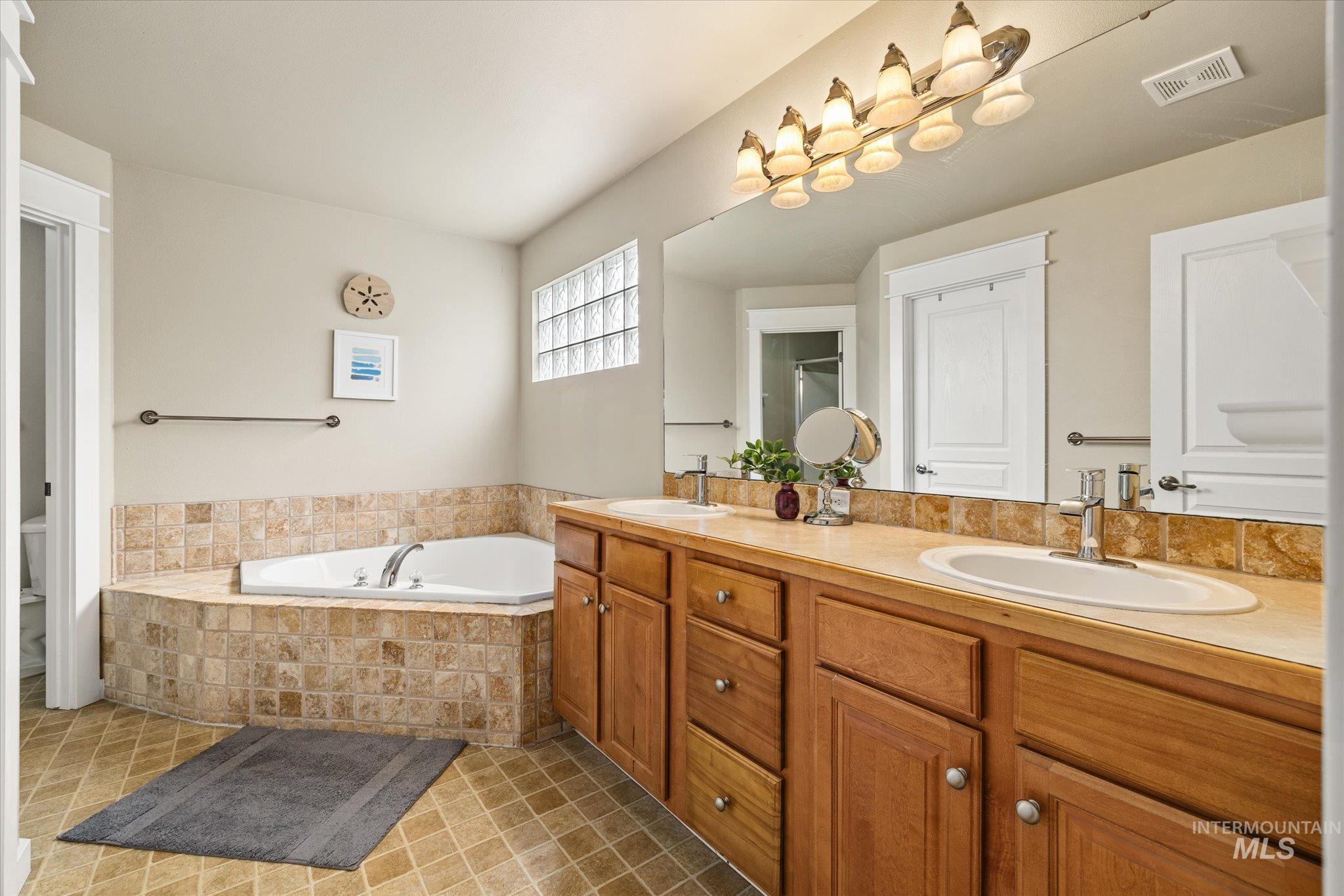 Full bath with a garden tub, double vanity, and light tile patterned flooring