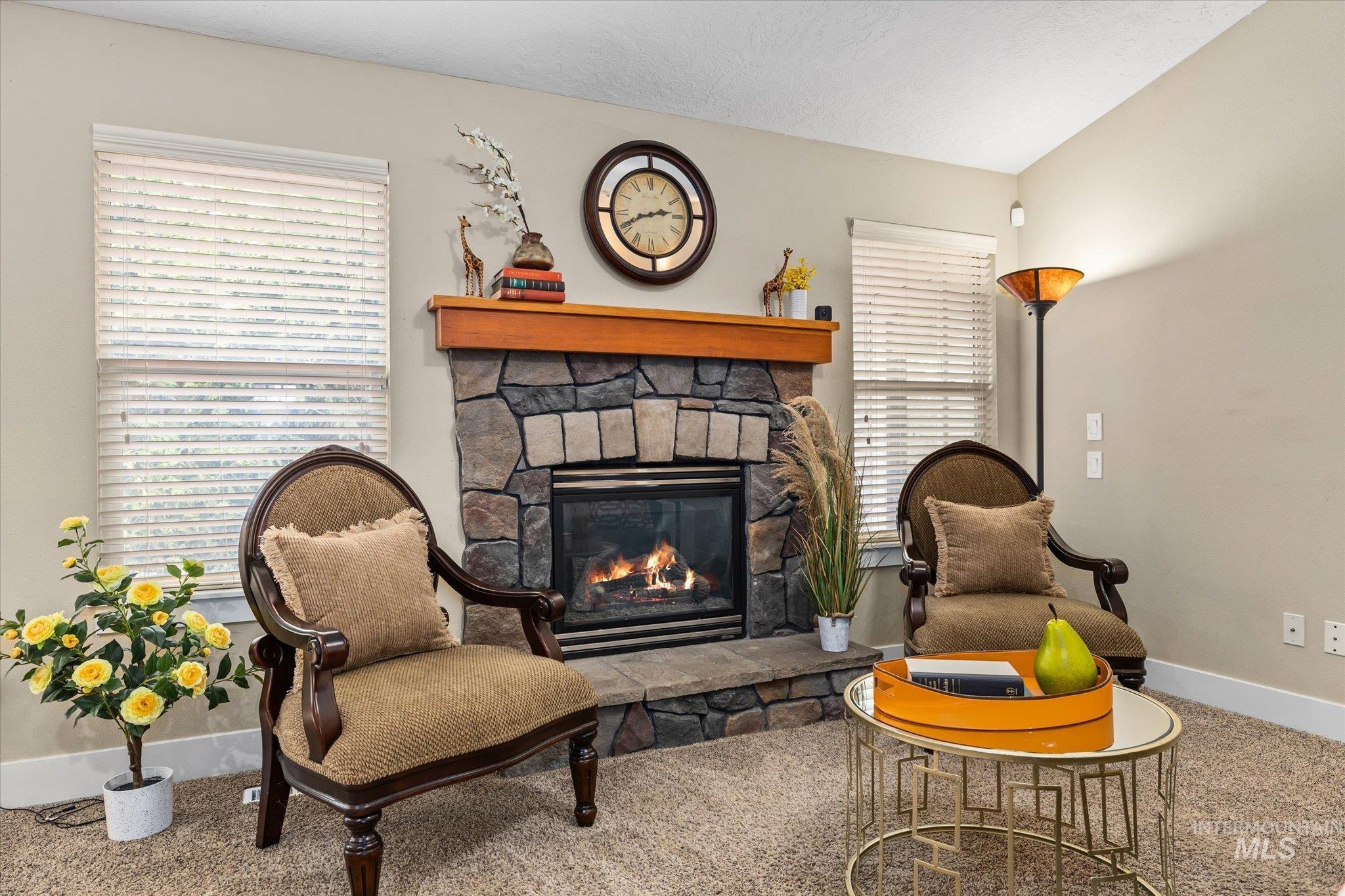 Living area featuring carpet flooring, a fireplace, and vaulted ceiling