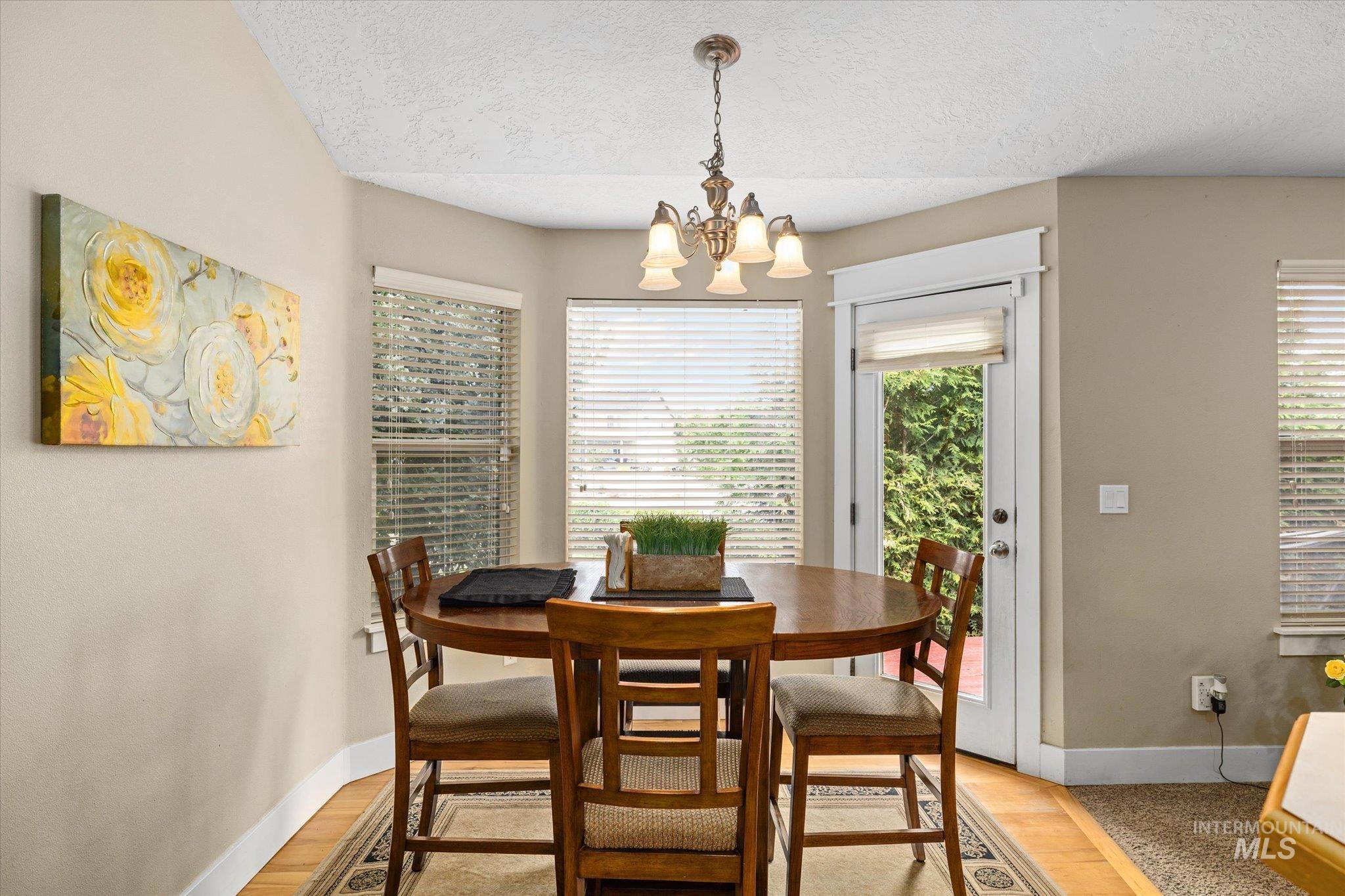 Dining space with a textured ceiling, light wood-style flooring, and a chandelier