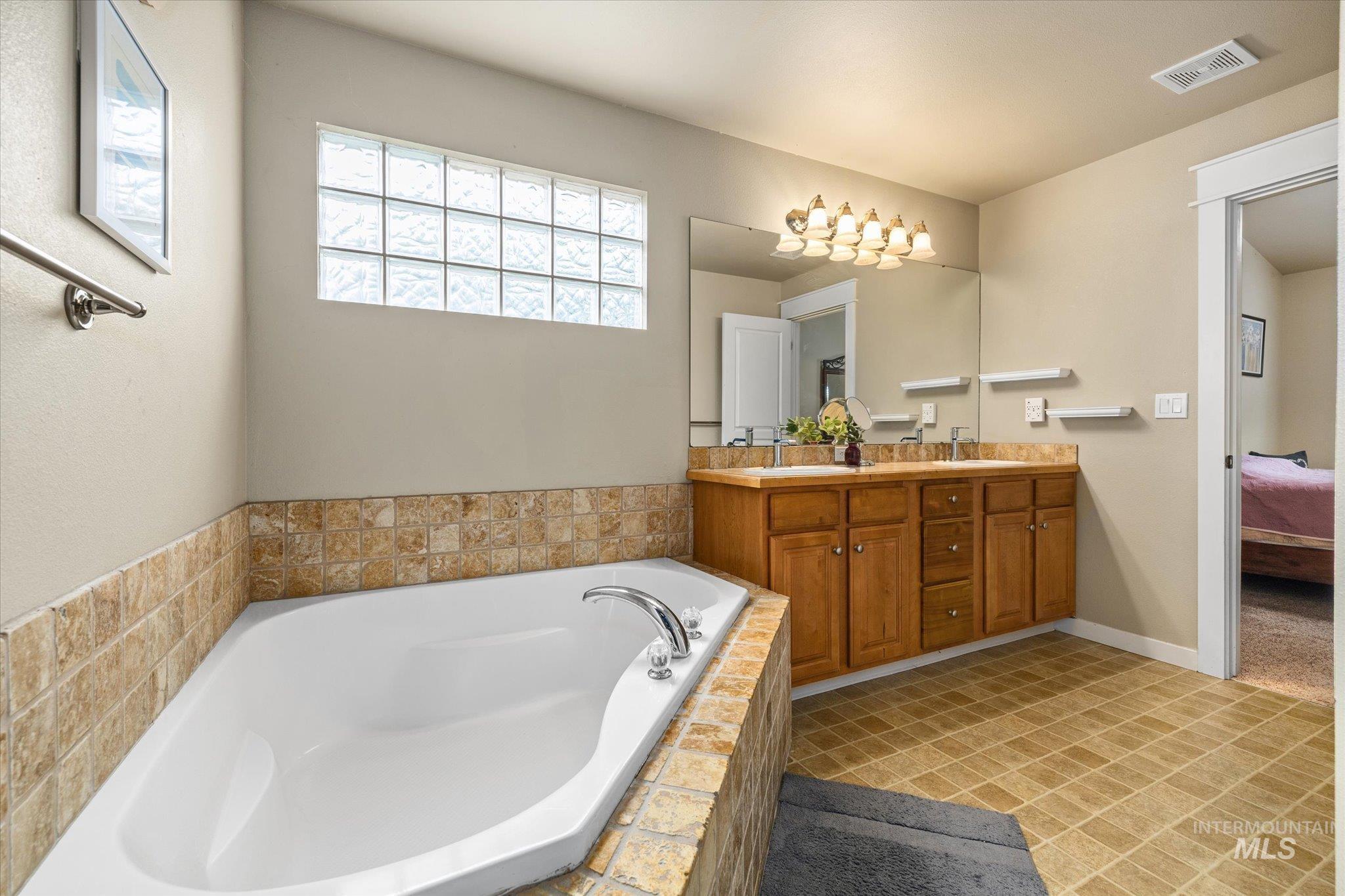 Bathroom featuring a garden tub, double vanity, and ensuite bath