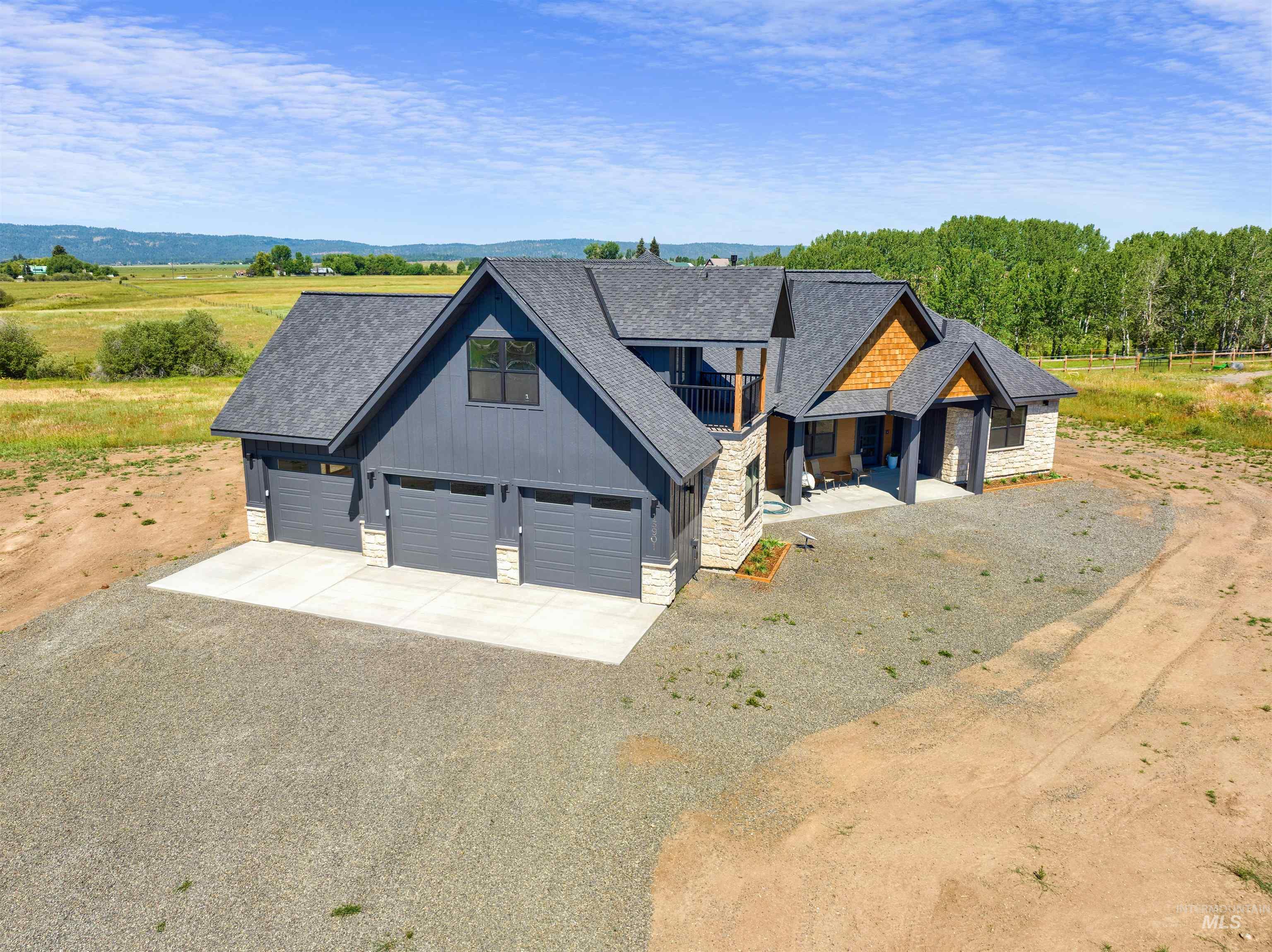 View of front of property featuring stone siding, driveway, and roof with shingles