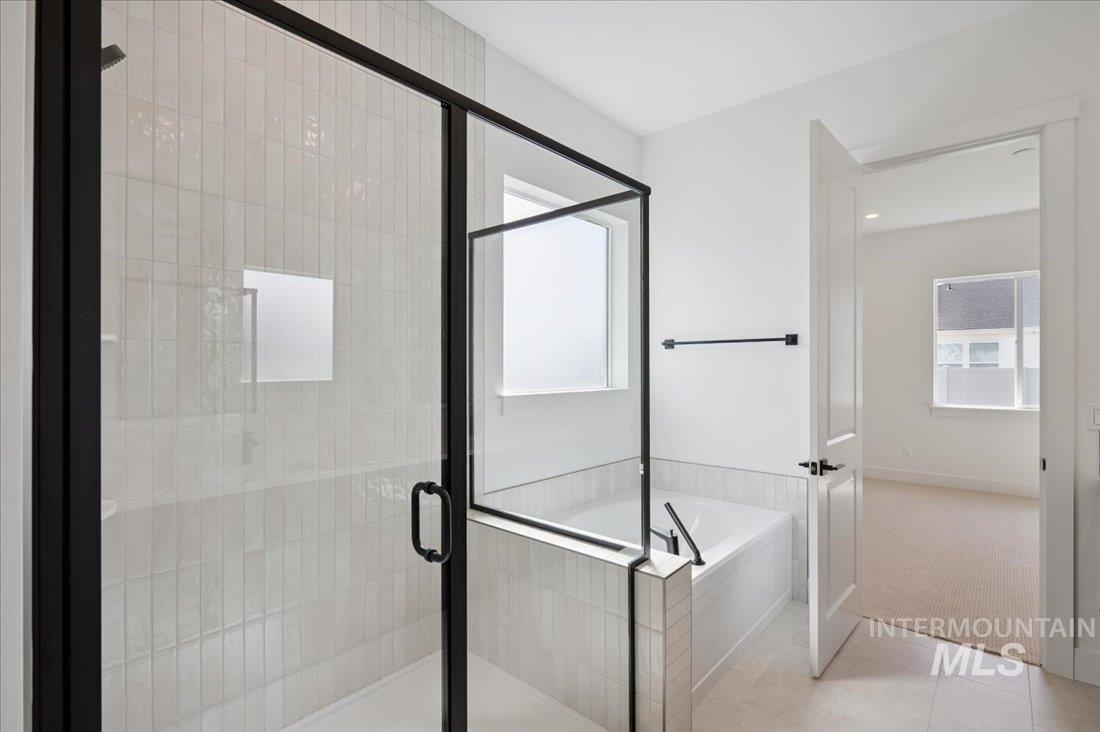 Full bathroom featuring a garden tub, a stall shower, light tile patterned floors, and light colored carpet