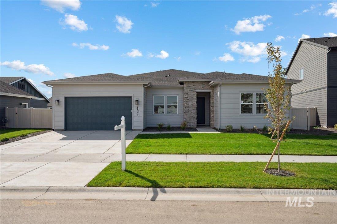 View of front of house with concrete driveway, an attached garage, and stone siding