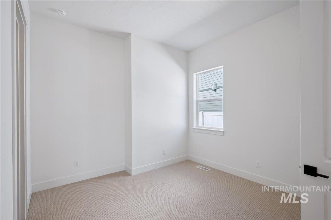 Spare room featuring carpet flooring and baseboards