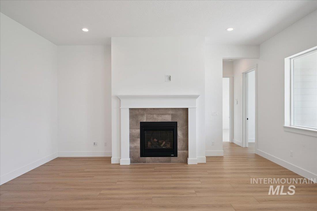 Unfurnished living room featuring light wood-style floors, a tiled fireplace, and recessed lighting