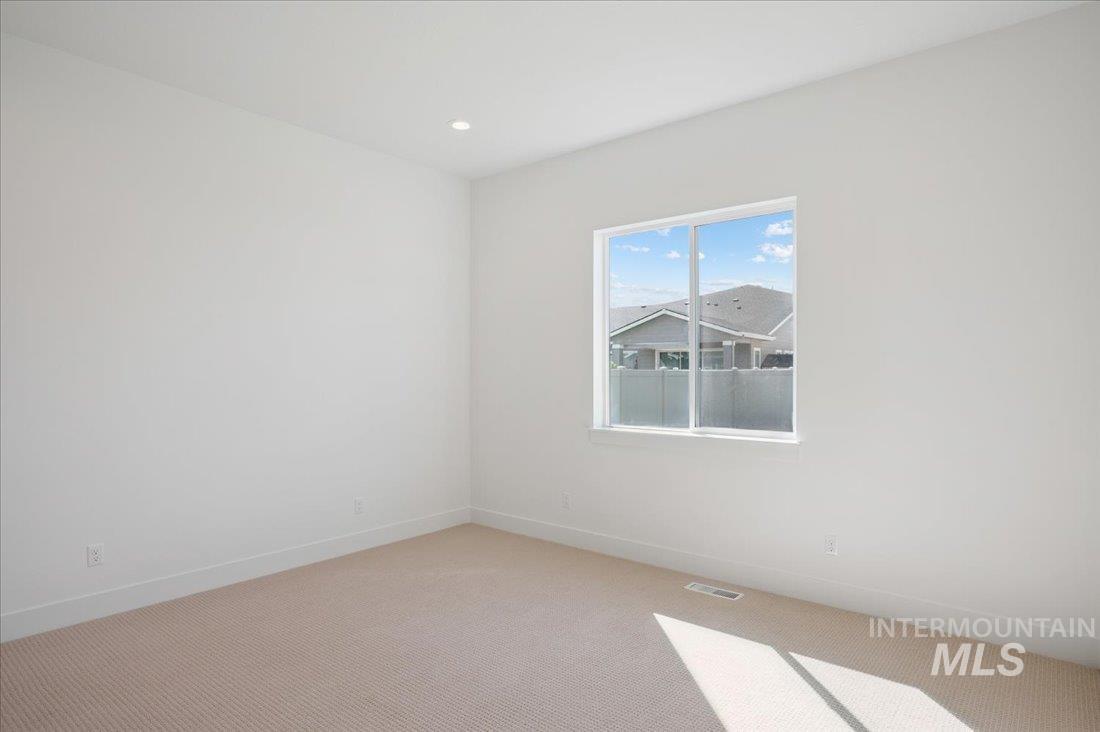 Empty room with light carpet and recessed lighting