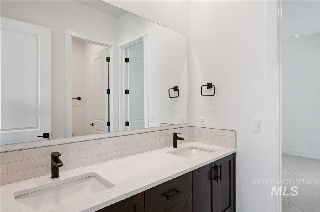 Bathroom featuring double vanity and backsplash