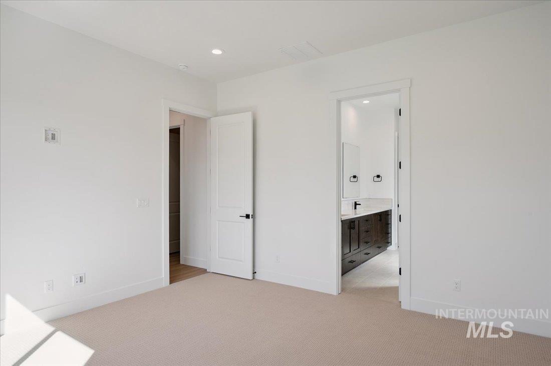 Unfurnished bedroom featuring light colored carpet, connected bathroom, and recessed lighting