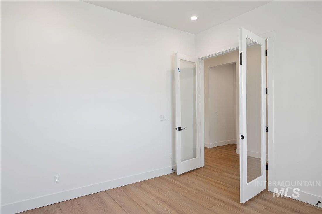 Unfurnished room featuring light wood-style flooring and french doors