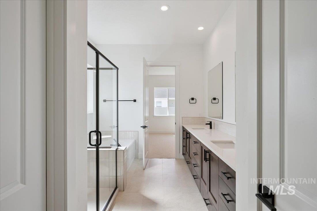 Bathroom featuring double vanity, a bath, a shower stall, recessed lighting, and light tile patterned floors