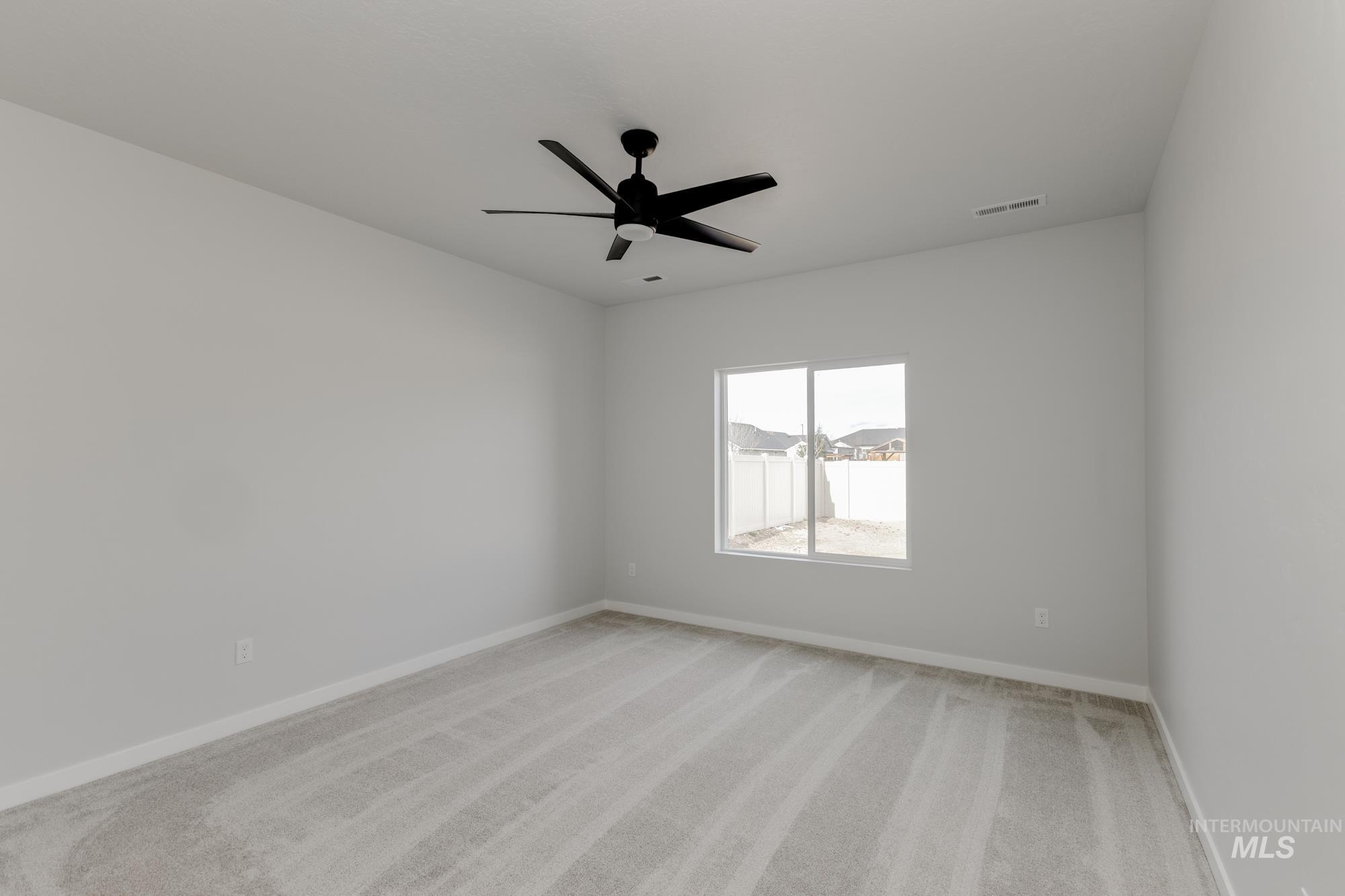 Spare room with light carpet and a ceiling fan