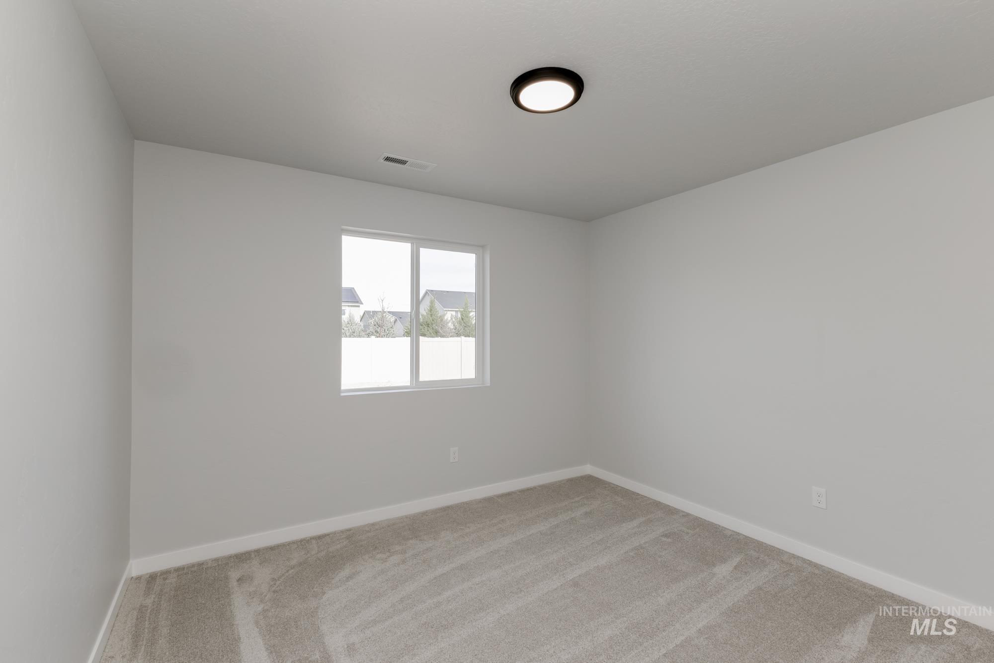 Empty room with light colored carpet and baseboards