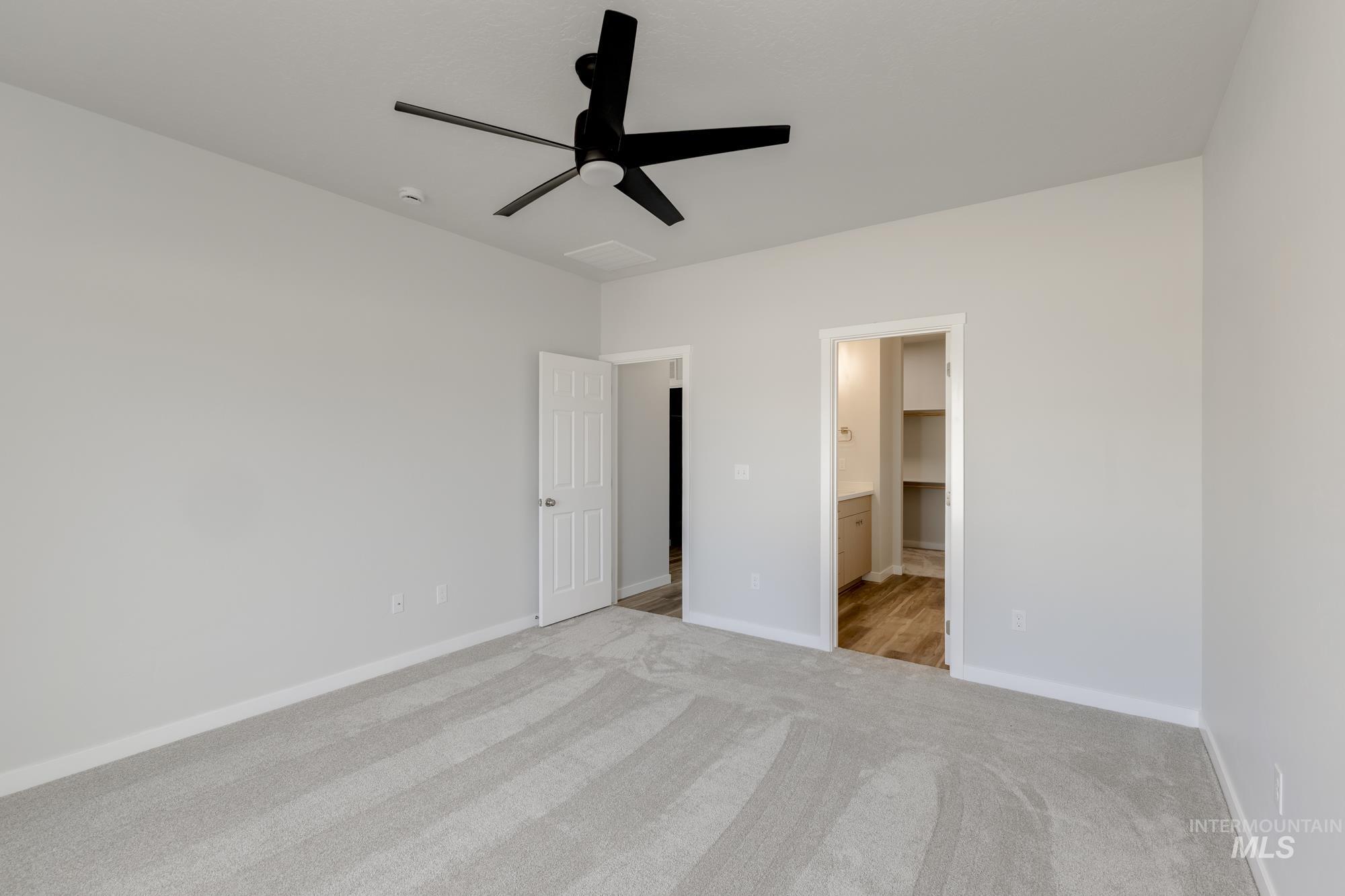 Unfurnished bedroom with a ceiling fan, light colored carpet, and ensuite bathroom