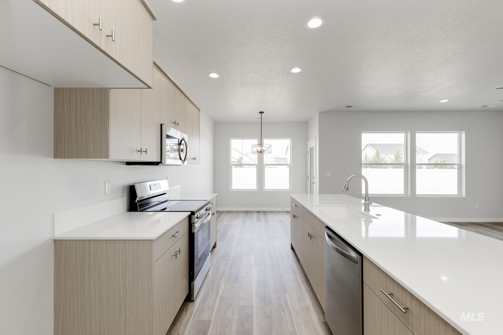 Kitchen featuring light brown cabinets, stainless steel appliances, decorative light fixtures, modern cabinets, and recessed lighting