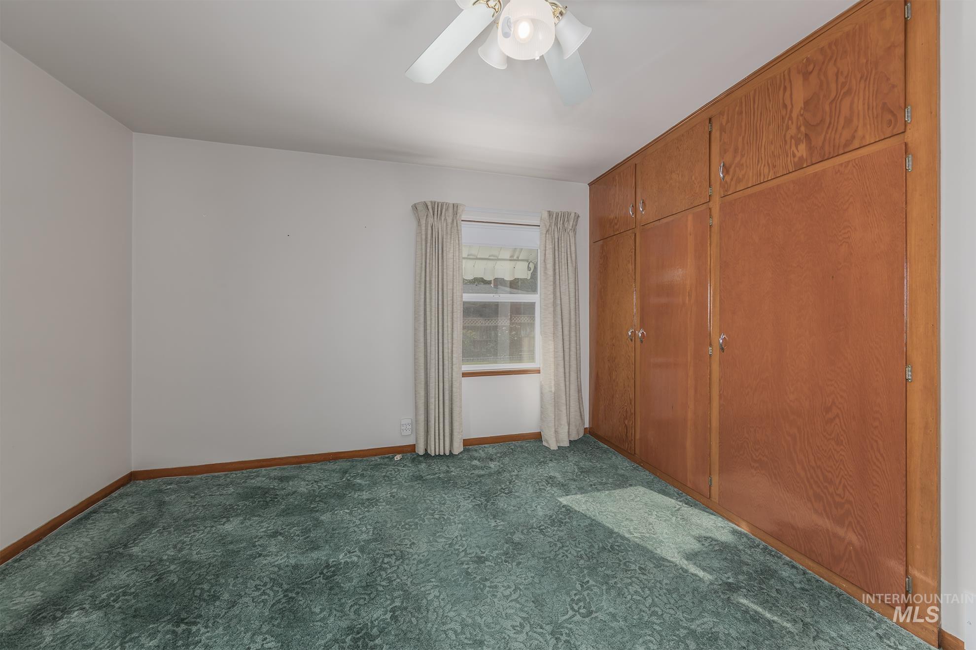 Unfurnished bedroom with dark colored carpet, ceiling fan, and a closet