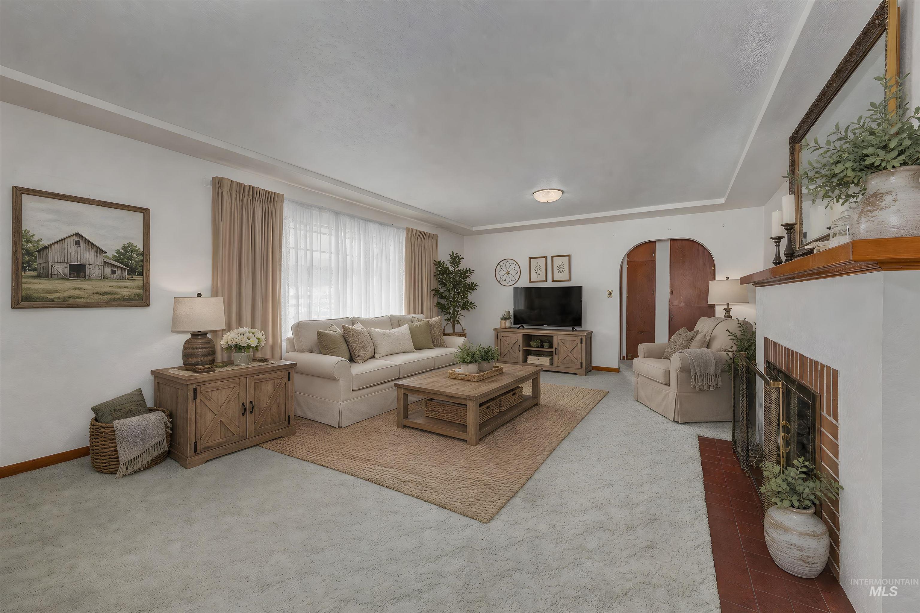 Living area featuring light-toned carpeting and a fireplace with a brick surround