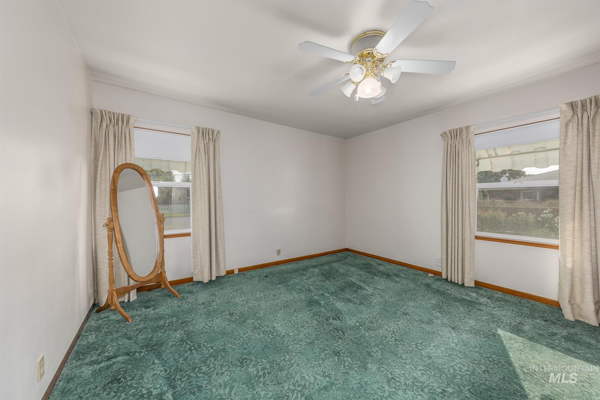Carpeted empty room featuring baseboards and a ceiling fan