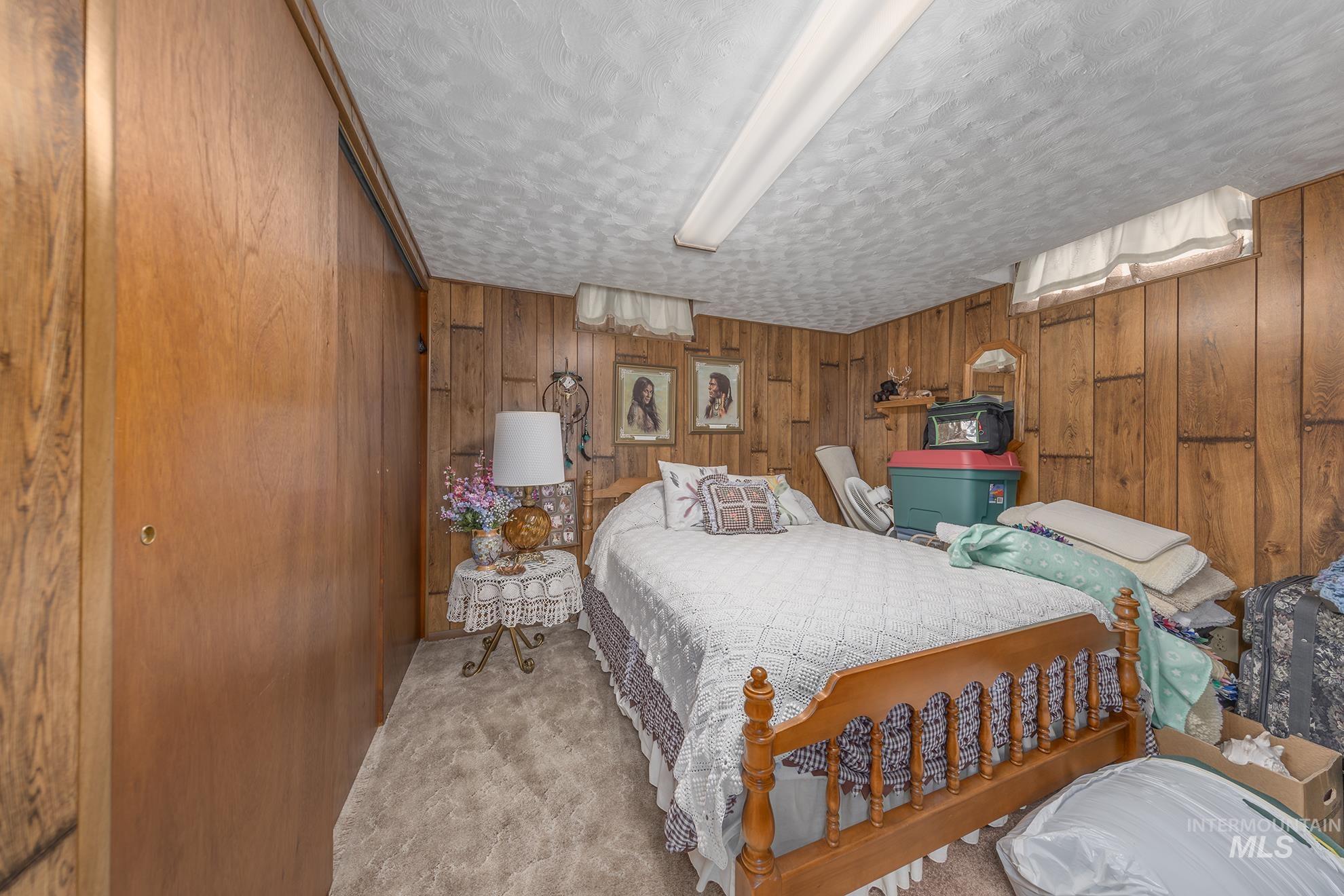 Carpeted bedroom featuring wooden walls and a textured ceiling