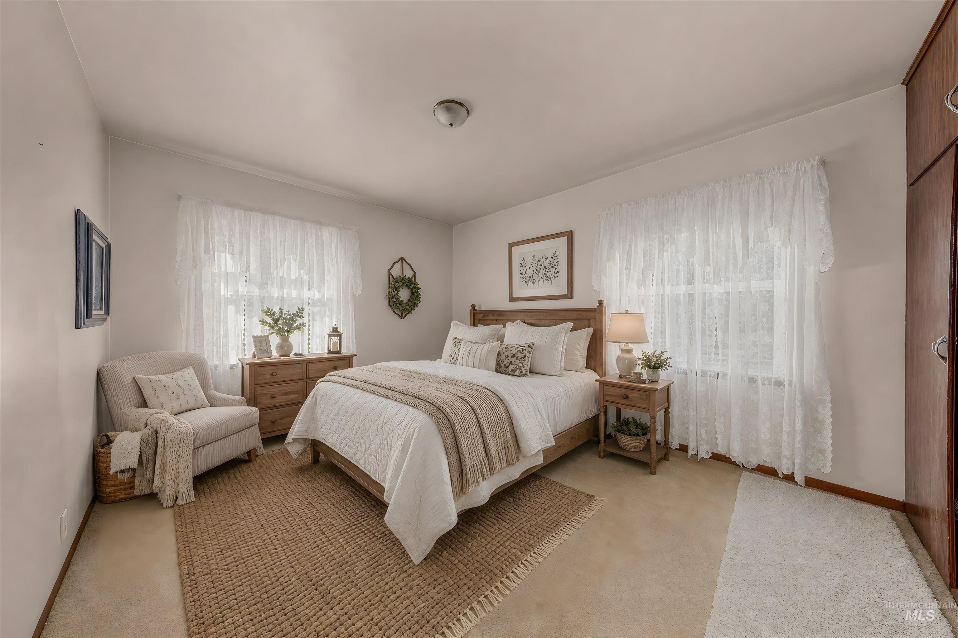 Bedroom featuring light-colored walls, carpeted flooring, and a large window with sheer white coverings