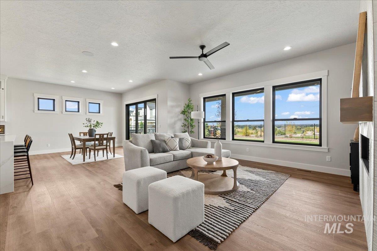Living area with a ceiling fan, light wood-style flooring, a textured ceiling, a fireplace, and recessed lighting