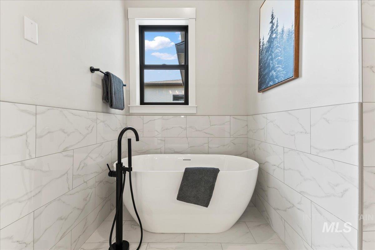 Full bathroom with tile walls, a freestanding tub, and wainscoting