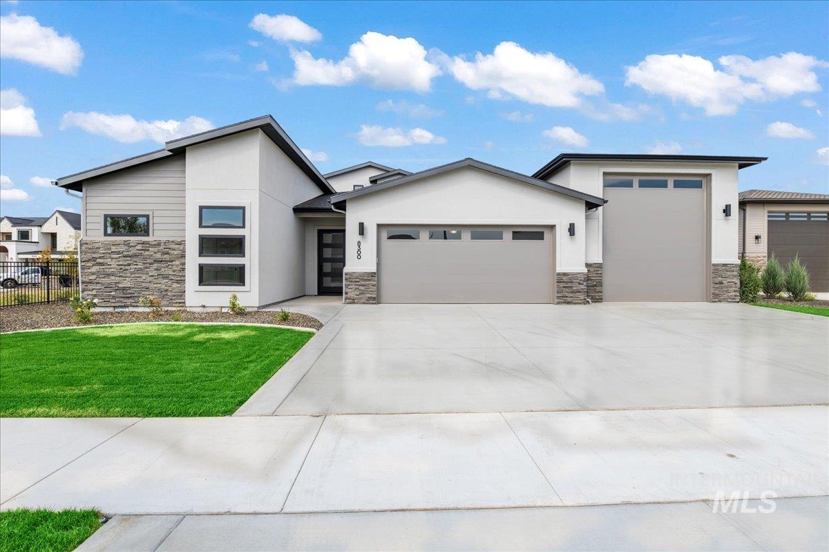 View of front facade with stone siding, an attached garage, stucco siding, and concrete driveway