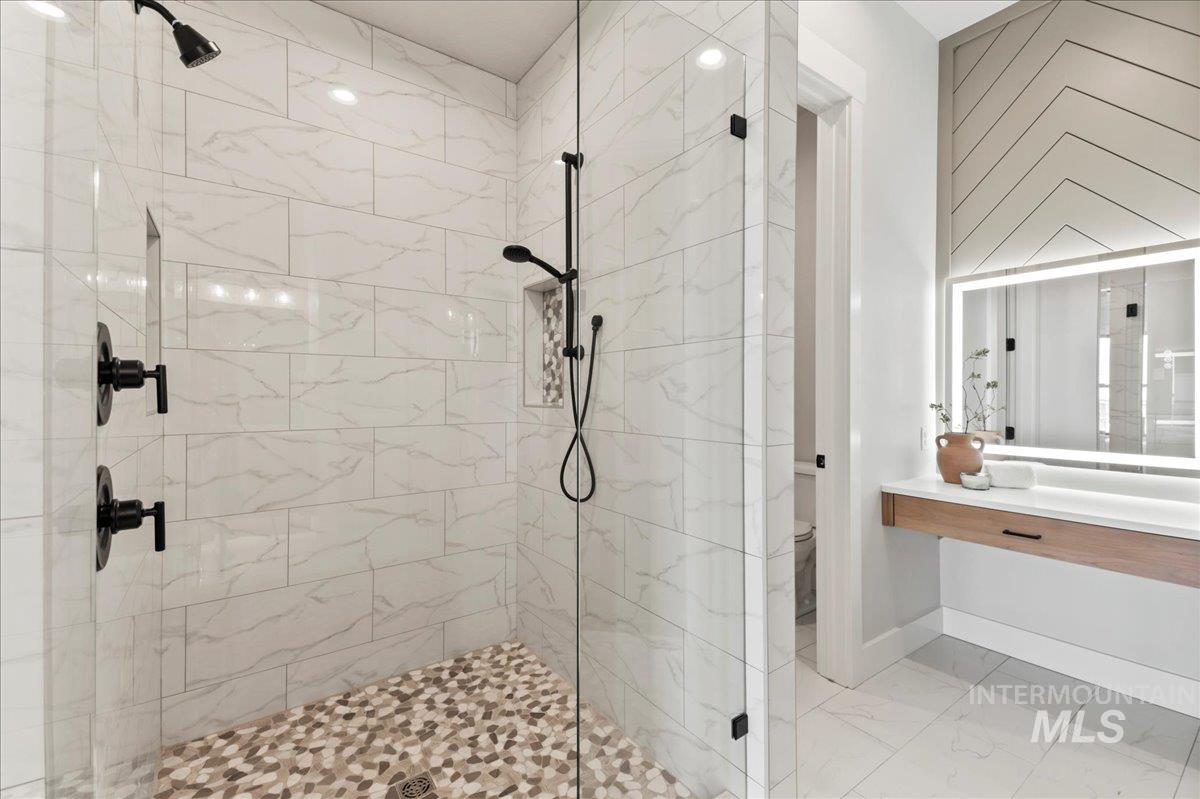Bathroom featuring a stall shower, light marble finish floors, and vanity