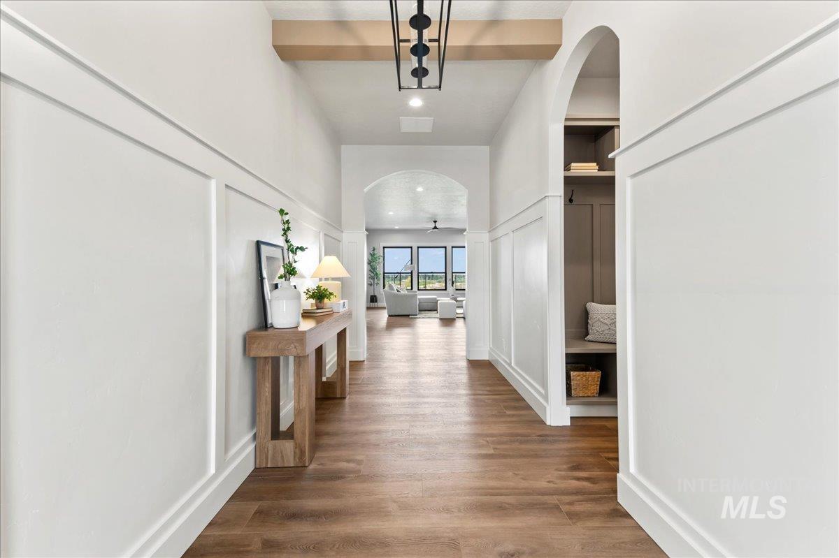 Hall with arched walkways, a decorative wall, and wood finished floors