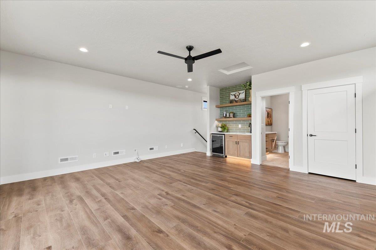 Unfurnished living room featuring recessed lighting, light wood finished floors, wine cooler, and ceiling fan